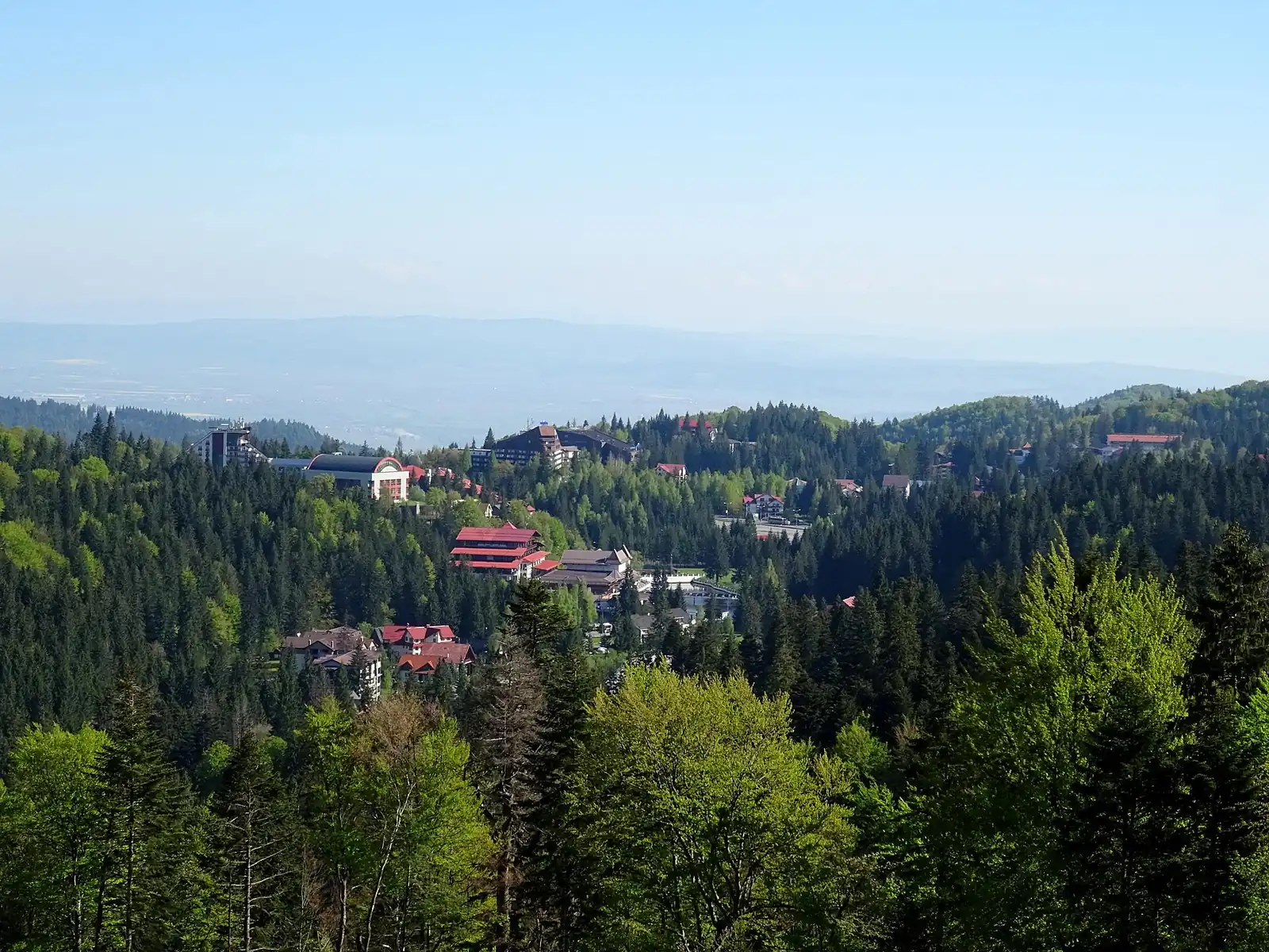 Vedere de vară asupra stațiunii Poiana Brașov, înconjurată de pădurile Postăvarului